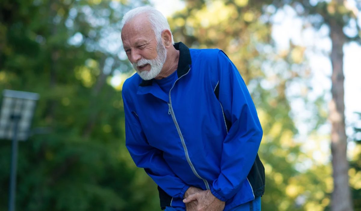 پیرمردی در حال ورزش در پارک که درد ادرار کاذب او را آزار داده